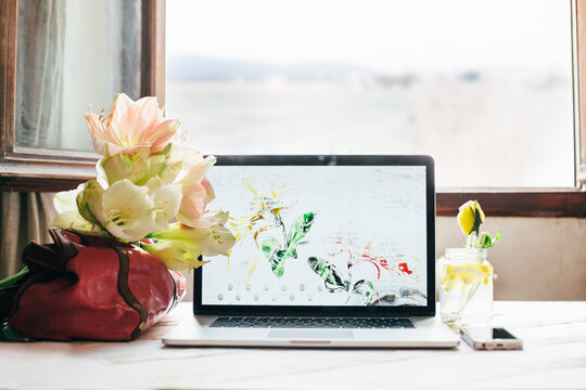 Notebook and healthy drink with a bouquet of amarilis on a woman's desk