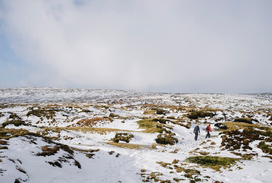 Young couple exploring the snow covered moorland of Bleaklow.