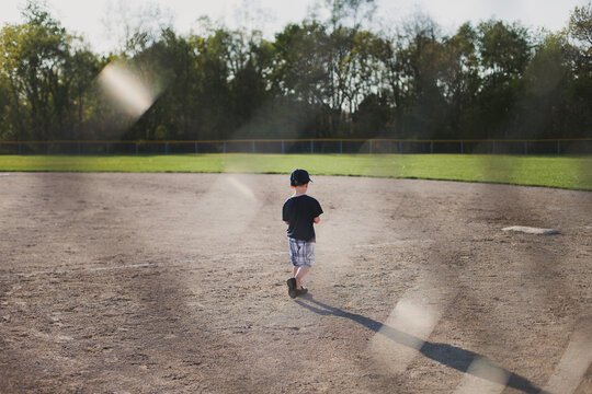 Young boy walks toward first base on baseball field