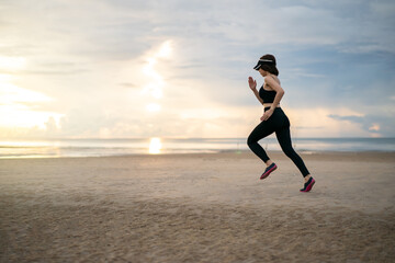 Fototapeta premium Side view of woman jogging on beach in the morning.