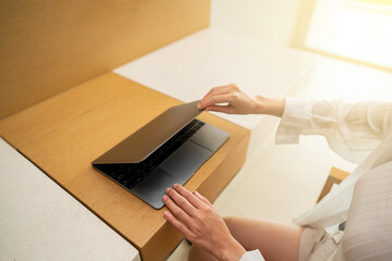 Woman hand open or close laptop on wood table.