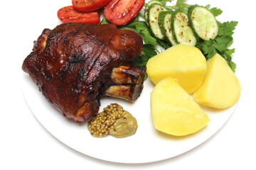 Fried pork knuckle with vegetables lies on a white plate