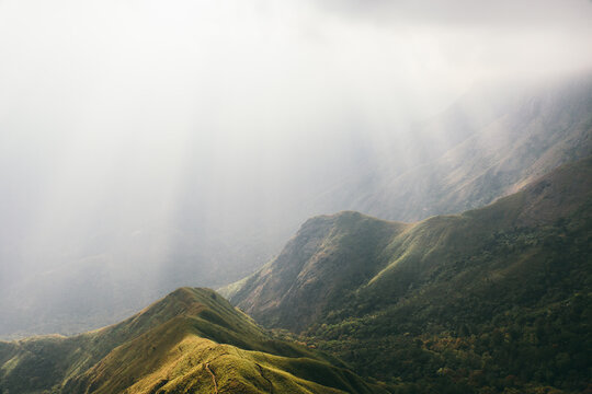 Green hills on mountain landscape with light rays passing through the clouds - Top Station, Kannan Devan hills, near Munnar on Kerala and Tamil Nadu border, India.