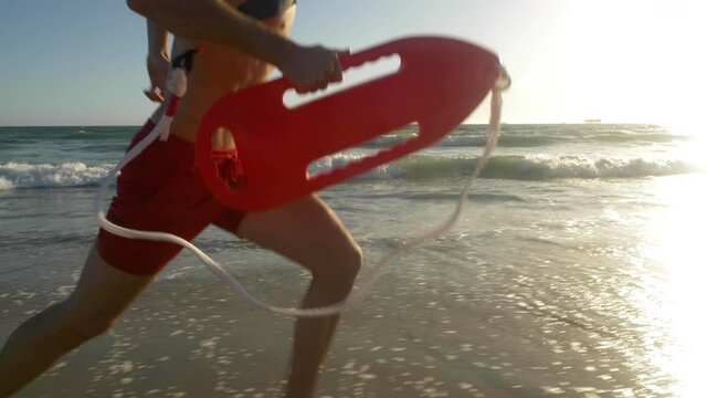 Male lifeguard running along the beach