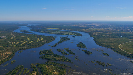 Aerial panorama view of Zambesi River delta ahead of Victoria Falls, bush land and village Livingstone in the background at the border of Zimbabwe and Zambia.