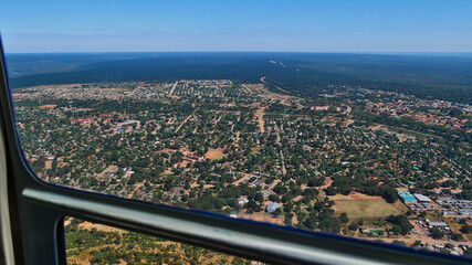 Fototapeta na wymiar Aerial view from helicopter over famous Victoria Falls town and bush land at the border of Zimbabwe and Zambia on a sunny day with blue sky.