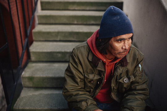 Reflective older, native homeless man sitting on steps