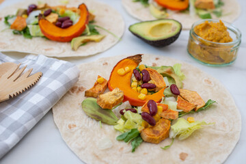 Open vegan tortilla wraps with sweet potato, beans, avocado and pumpkin