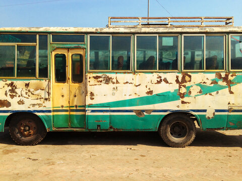 An old bus with scrape marks on the side.