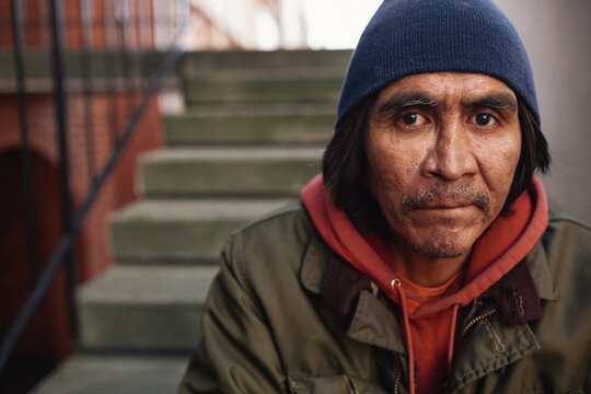 Portrait of older, native homeless man siting on steps