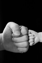 B&W photo,Fist of Dad and Newborn Baby,isolated on black background.