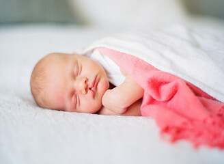 Newborn baby boy with cleft lip sleeping on a bed
