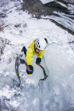Athlete ice climbing steep icefall