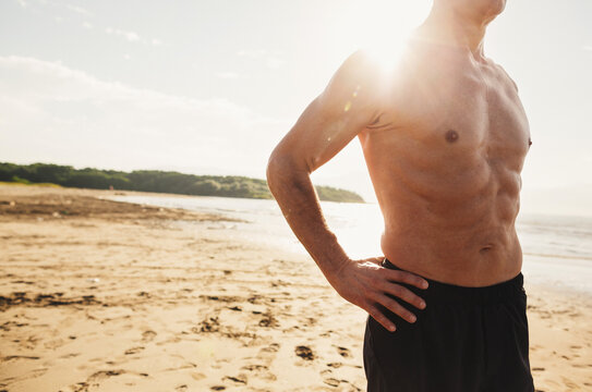 Sweaty chest of senior man - in great shape - shirtless on beach in morning sunshine