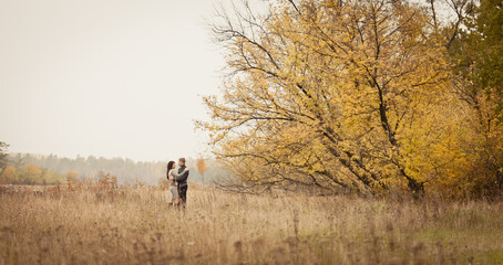 Naklejka na ściany i meble couple on autumn walk outdoors. Two lovers in autumn park. Love and tender touch. Foggy cloudy day filled with the warmth of love. Beautiful autumn landscape for couple