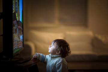 1 year old boy watching television in the dark