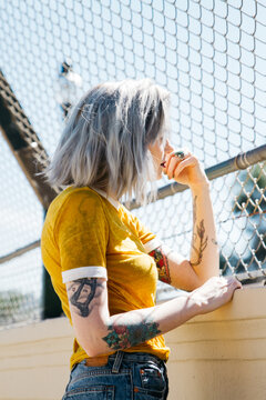 portrait of urban young female in city next to chain link fence