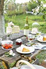 Wedding. Banquet. The chairs and table for guests, decorated with strawberry, served with cutlery, crockery and covered with a tablecloth. The table stands on a green lawn in the backyard banquet area