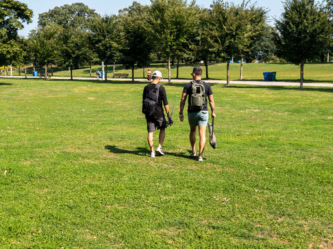 Men Going Fishing Walking Through The Park With Fishing Pole And Case