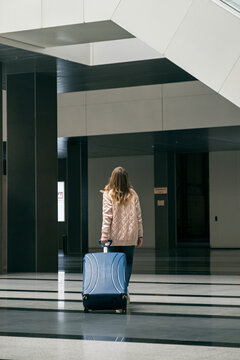 Back view of young woman walking away in airport building