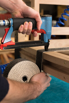 Webbing being attached with a pneumatic stapler as part of the renovation process of a sofa.