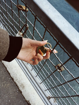Young woman holding heart padlock on bridge of love
