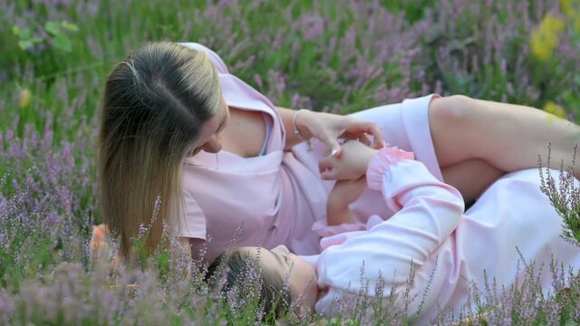 Happy Mom Plays With Little Daughter Outdoors. Mum and her Child Lie on the Grass in the Park. Happy mother's day