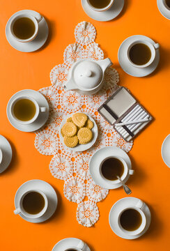 Coffee cups with cookies on tablecloth on orange background / ook from above
