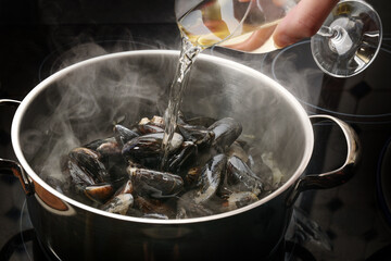 Steaming mussels in a pot are deglazed with white wine, cooking concept for a delicious seafood...