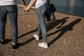 Close up of romantic couple hold hands and walk along the shore