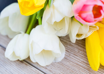 The bouquet of tulips lies on a wooden table. Beautiful bouquet of white and yellow tulips. Close up 