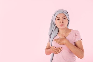 young woman with breast pain touching chest on pink background