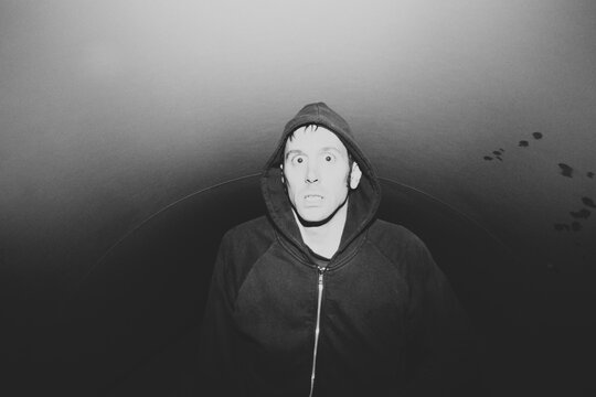 Portrait of man with surprised expression on face, walking through dark urban tunnel