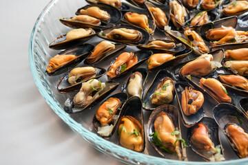 Freshly cooked blue mussels with onion and herbs served on a glass plate