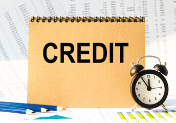 Notebook, pencils and clocks on the table with financial papers. your text CREDIT