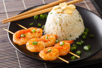 Butter garlic rice with fried shrimps on skewers close-up in a plate on the table. horizontal