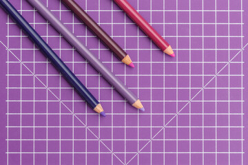 purple coloured pencils on a purple grid background