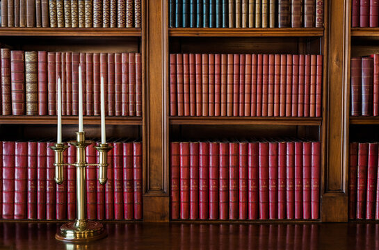 Books organized on old library shelf with antique candlestick