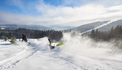 Skiing racing down from high mountain. Skier making unlucky maneuver on turning and falling on snow. Back view of two skiers. Outstripping, falling down, defeat concept. Panoramic mountain view.