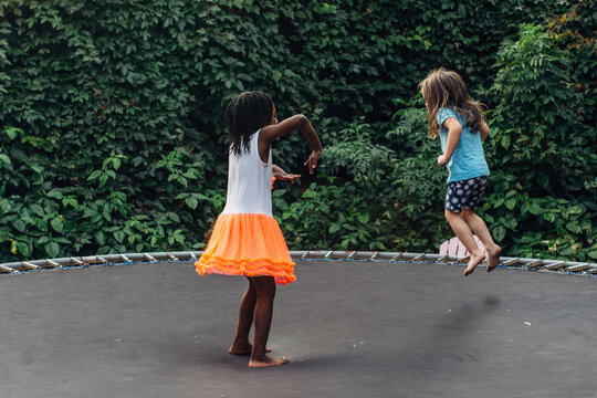Black and Caucasian girls on trampoline