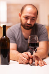 Man feeling wasted and emotional depressed after drinking glass of red wine. Unhappy person disease and anxiety feeling exhausted with having alcoholism problems.