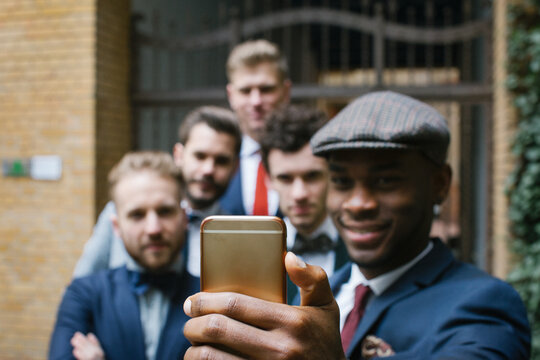 Young Black Man Taking Selfie of Five Smiling Friends in Suits