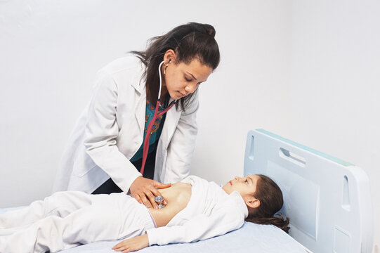 Doctor is checking a girl's stomach with a stethoscope