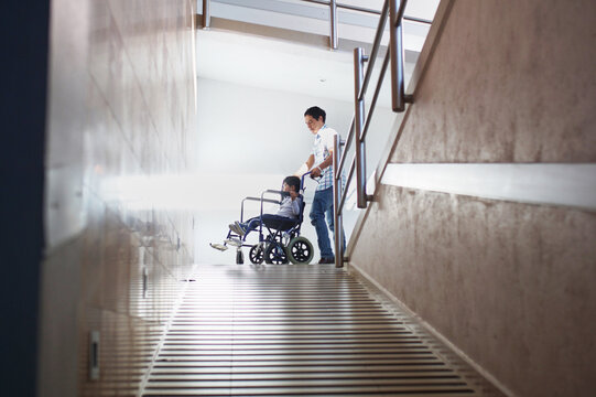 Dad pushes his son down a ramp in a wheelchair
