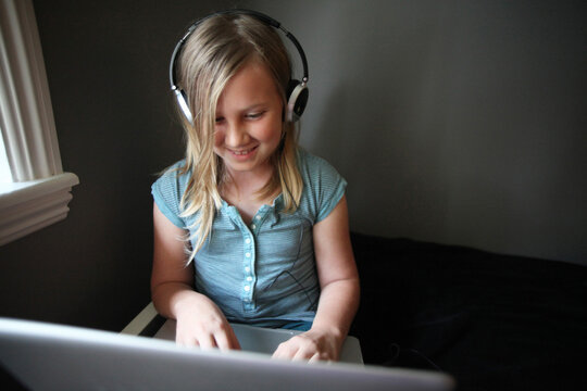 Wide Angle View Of Girl Wearing Headphones On Laptop