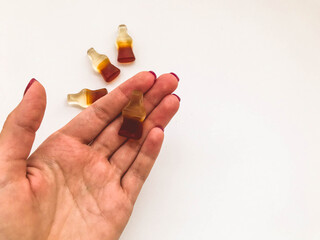 marmalade candies. sweets in the shape of a bottle of lemonade lie on the hand of a girl with a red manicure. delicious, chewy dessert for kids. gummy gummies