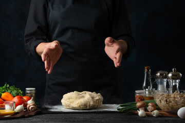 Making dough by professional chef hands on black table background. Backstage of preparing pie. Bakery concept.