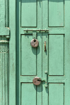 Two padlocks on a green door