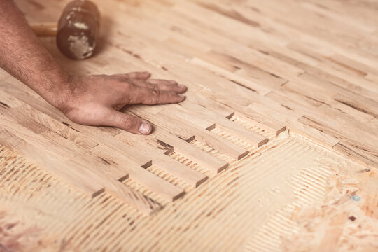 Worker Installing Wood Parquet. Carpenter On Work Putting Wood Parquet Pieces, Home Renovation, Close Up