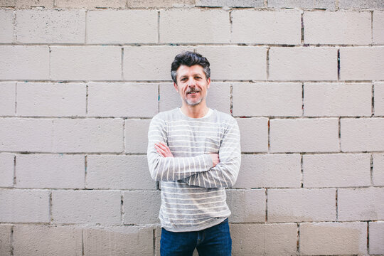 Portrait of a mature man standing in front of a wall.